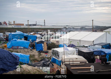 La vista sulla giungla campo profughi a Calais, Francia. Tende, tettoie, pensiline e roulottes con la grande industria in background. Foto Stock