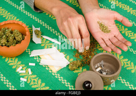 Mani femminili il rotolamento di un giunto circondato da gli ingredienti principali Foto Stock