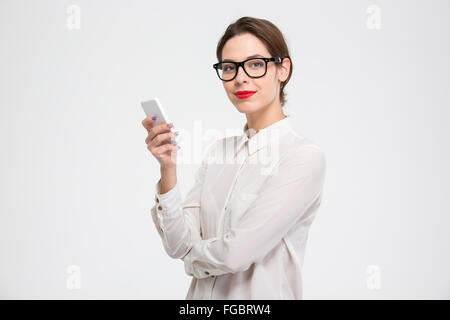 Felice fiducioso young business woman in bicchieri utilizza lo smartphone su sfondo bianco Foto Stock