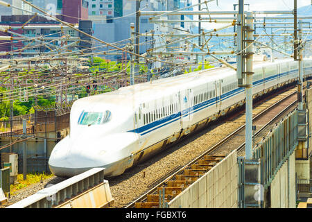 Coda di una partenza Shinkansen alta velocità del treno bullet lasciando Kyoto tra fili e edifici visto da sopra Foto Stock