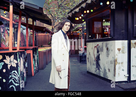 Uomo in piedi in una strada in Shoreditch con un mantello bianco Foto Stock