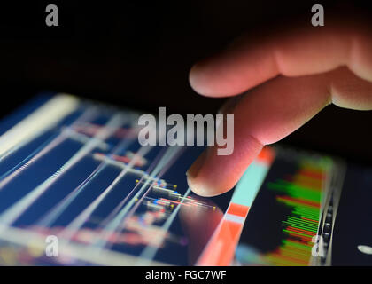 Traders finger using the touchscreen of a digital tablet displaying a financial Market graph. close up. Foto Stock