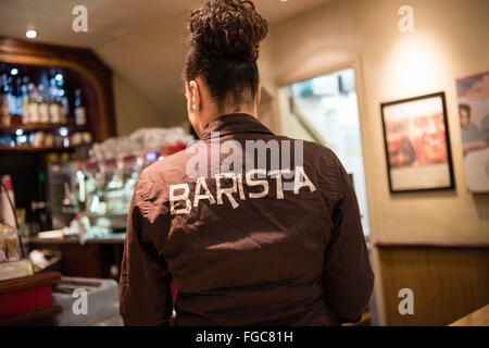 All'interno di una Costa Coffee shop con branding, una donna barista e macchine per il caffè e delle pile di bicchieri di carta Foto Stock