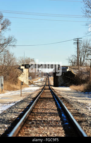 Una singola traccia passa sotto un altra linea guida sul suo cammino verso l'orizzonte in northeastern Illinois comunità di Wayne, Illinois, Stati Uniti d'America. Foto Stock