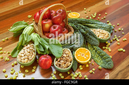 Salute composizione alimentare con le mele nel cestello, verde di foglie e i dadi collocato su un tavolo di legno. Foto Stock