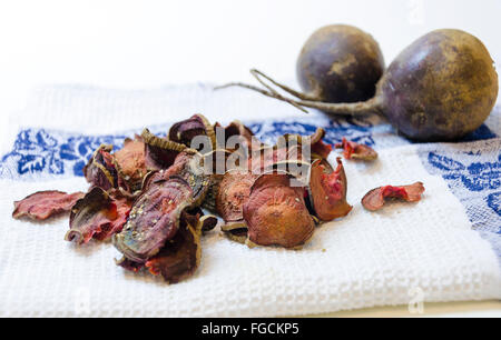 Round sottili scaglie di barbabietola cotta al forno con origano e sale e mature radici di barbabietola in uno sfondo bianco. Una sana e vegeta Foto Stock