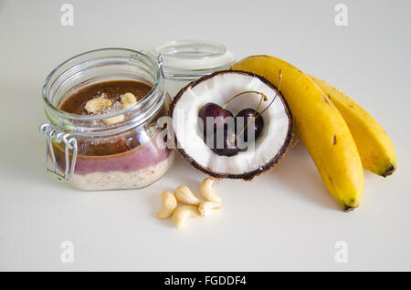 Cherry banana di noce di cocco per tutta la notte di avena con crepe aperte coco, banana, anacardi mescolati con semi di Chia e crema di ciliegio in un mason j Foto Stock