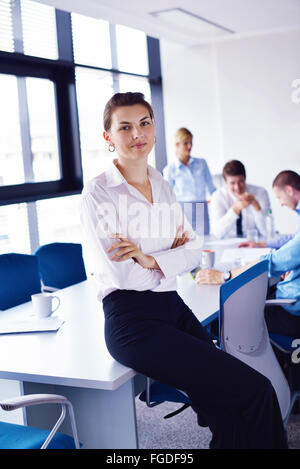 Business donna con il suo staff in background in ufficio Foto Stock