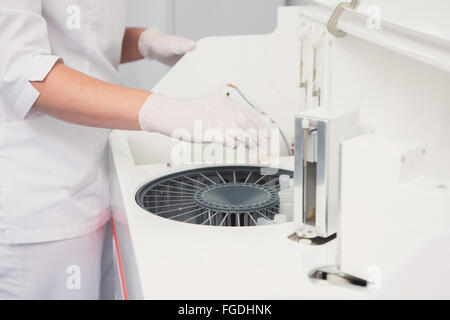 Lab tech il caricamento di campioni in un analizzatore per chimica Foto Stock