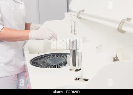 Lab tech il caricamento di campioni in un analizzatore per chimica Foto Stock