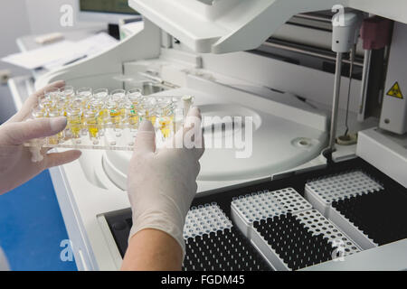 Lab tech il caricamento di campioni in un analizzatore per chimica Foto Stock