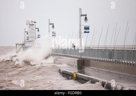 Port Stanley, Canada - Ottobre 3,2015. Onde infrangersi oltre il molo pubblico in Port Stanley, come un giovane cerca di rimanere a secco. Foto Stock