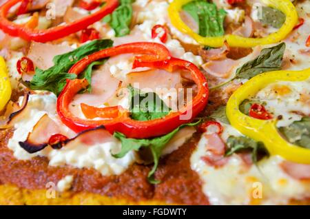 Cotta al forno a pizza e rabboccato con halloumi, cottage, mozzarella, spinaci, Turchia, prosciutto, peperoni rossi e gialli, peperoncino, basilico un Foto Stock