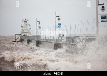 Port Stanley, Canada - Ottobre 3,2015. Onde infrangersi oltre il molo pubblico in Port Stanley, come un giovane cerca di rimanere a secco. Foto Stock