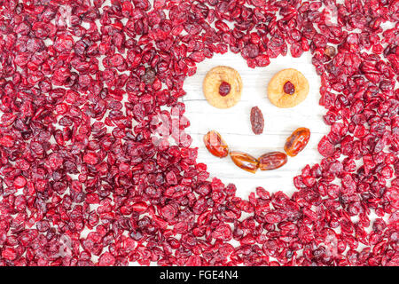 Divertente faccia fatta di frutta secca su bianco sullo sfondo di legno. Foto Stock