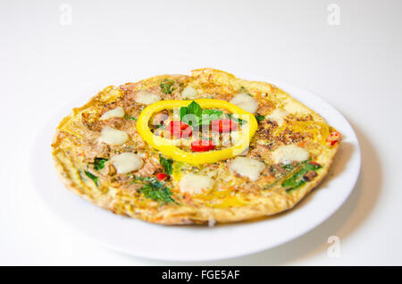 Un spinaci, peperoncino, Menta e Pepe frittata in un piatto isolato su sfondo bianco. Una dieta sana frittata di farina. Foto Stock