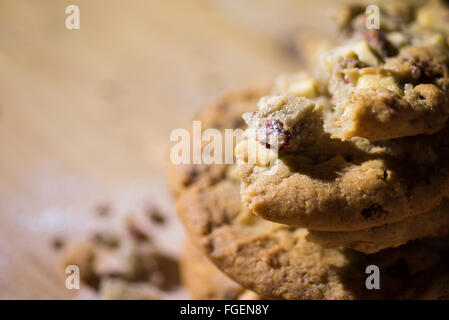 Biscotti al cioccolato bianco e mirtilli impilati su un pannello di legno Foto Stock