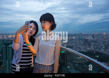 Ragazza amici presi selfies a con una vista panoramica e verticale di Bangkok da scirocco sul tetto. Thailandia. Asia, Bangkok, capi Foto Stock