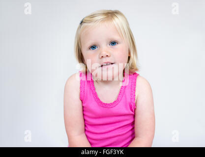 Ritratto di una giovane ragazza con corti capelli biondi e gli occhi blu di indossare un giubbotto rosa sorridente Foto Stock
