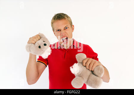 L'uomo strappando la testa fuori un simpatico peluche orsetto urlando in un momento di collera Foto Stock