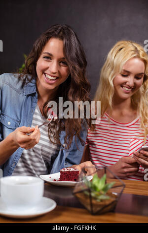 Sorridente brunette godendo di una pasticceria Foto Stock