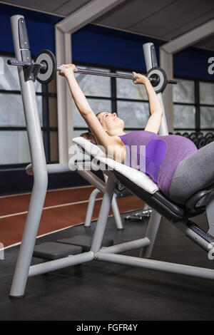 Sorridente donna incinta il sollevamento barbell Foto Stock