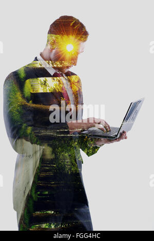Doppia esposizione di business man che lavora sul computer portatile e alley con alberi e sunrise Foto Stock