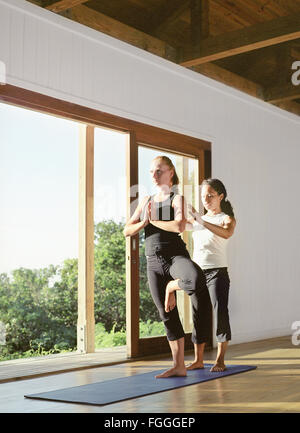 Un istruttore di yoga aiuta a uno studente durante una lezione di yoga al Parrot Cay Resort. Parrot Cay, Turks e Caicos. Foto Stock