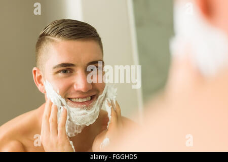 L'uomo la Messa della schiuma da barba sulla faccia Foto Stock