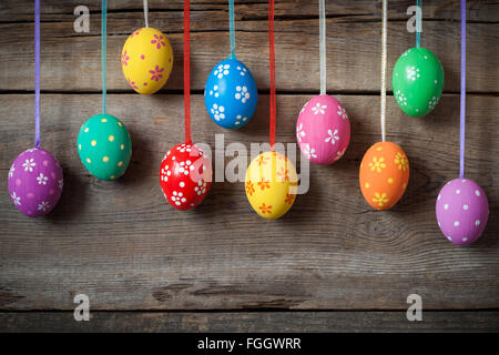 Appendere le uova colorate sul rustico sfondo di legno Foto Stock