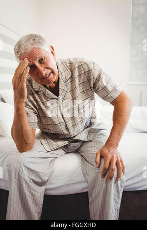 Frustrati senior uomo seduto sul letto Foto Stock