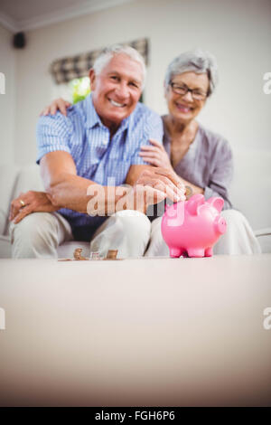 Senior uomo mettendo le monete nel salvadanaio Foto Stock