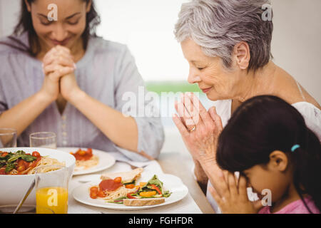 Famiglia di pregare insieme prima del pasto Foto Stock