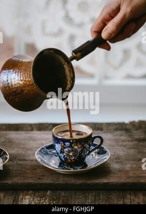 Una donna sta versando il caffè turco in una annata caffè turco cup. Foto Stock