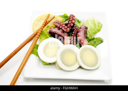 Mangiare uova e insalata di polpo con bacchette Foto Stock