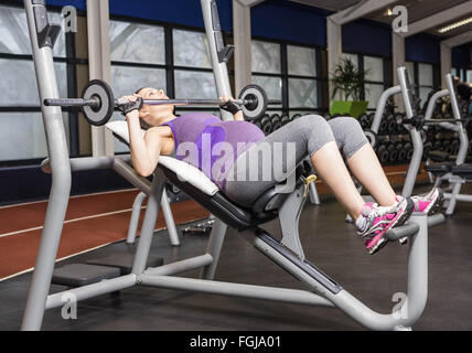 Sorridente donna incinta il sollevamento barbell Foto Stock