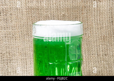 Bicchiere di Irish green birra su una tela dello sfondo. Simboli tradizionali della festa di San Patrizio Foto Stock