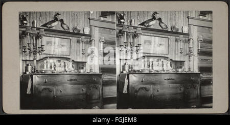 Una fotografia con una credenza con candelabri abbinati, scattata nella collezione Robert N. Dennis. L'immagine mostra la disposizione degli arredi e il design decorativo tipico dell'epoca. Foto Stock