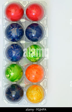 Colorate le uova di pasqua in una scatola di plastica, close up su sfondo bianco, verticale Foto Stock