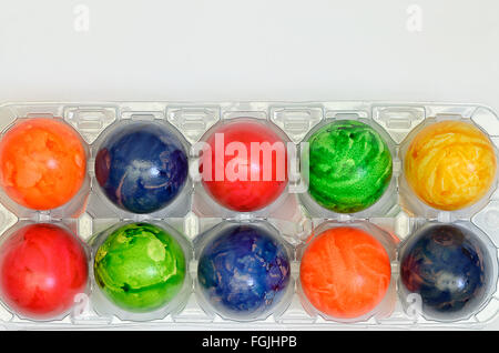 Colorate le uova di pasqua in una scatola di plastica, close up su sfondo bianco, orizzontale Foto Stock