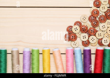 Bobina di fili e pulsanti sul tavolo di legno sfondo Foto Stock
