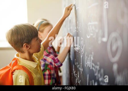 I bambini facendo le somme da lavagna di lezione Foto Stock