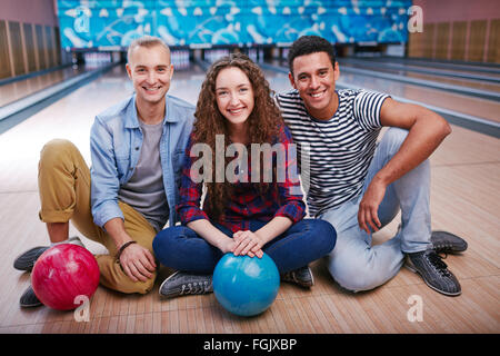 La gente è cordiale con le palle da bowling seduta sul pavimento a bowling Foto Stock