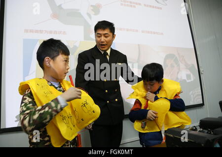 Binzhou, la Cina della provincia dello Shandong. Xx Febbraio 2016. Due bambini pratica auto-salvataggio con la guida di un istruttore durante un'antenna esperienza in attività Binzhou, est della Cina di Provincia di Shandong, Feb 20, 2016. I partecipanti delle attività si visita il piano della linea di produzione, apprendere conoscenze di aviazione, fare un pilota test psicologico ed hanno una bassa quota di esperienza dello spazio aereo tour. © Li Zhenping/Xinhua/Alamy Live News Foto Stock