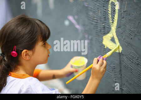 Young Teen girl dipinge il muro esterno Foto Stock