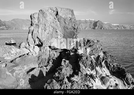 Santorini - il look di caldera tra i massi di pietra pomice con la Scaros Imerovigili ans in background. Foto Stock
