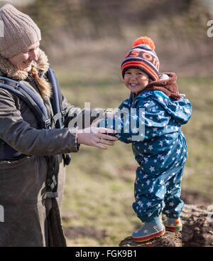 La madre e il bambino di tre anni ragazzo godendo il sole invernale all'aperto nella campagna. Foto Stock