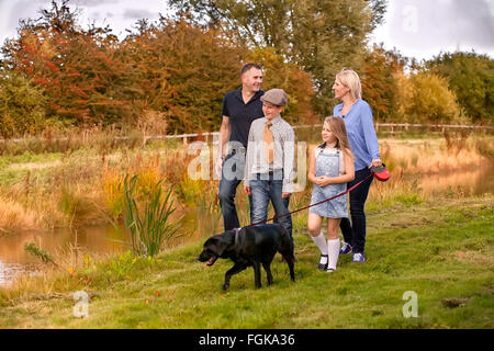 Famiglia passeggiate con il cane sul piombo per via navigabile. Foto Stock