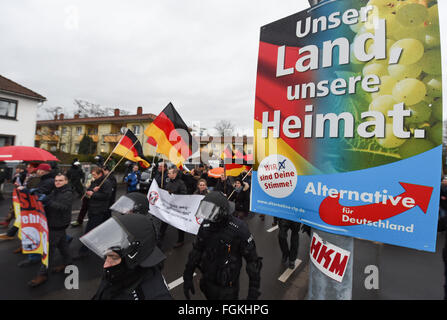 Mainz, Germania. Xx Febbraio 2016. Persone accompagnate dalla polizia a piedi passato un cartellone elettorale dall'alternativa per la Germania (AFD) partito che recita "Unser Land, unsere Heimat' (il nostro paese, la nostra casa) durante un raduno di "Karlsruhe wehrt sich' (lit. Karlsruhe combatte indietro), una propaggine di estrema destra europei patriottica contro l islamizzazione del West (Pegida) movimento contro il pubblico tedesco emittente Suedwestrundfunk (CFA) in Mainz, Germania, 20 febbraio 2016. Foto: ARNE DEDERT/dpa/Alamy Live News Foto Stock