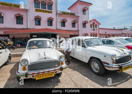 Ambasciatore classiche auto parcheggiate fuori un Indiano meridionale stazione ferroviaria Foto Stock